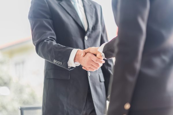Business man shake hands with business women agreeing on partnerships or introducing themselves for first time meet.