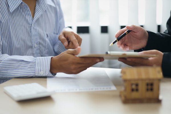 Real estate agent discussing about the terms of the purchase agreement and sign the documents to make the contract legally. Home sales, renting, leasing, mortgage and home insurance concept.